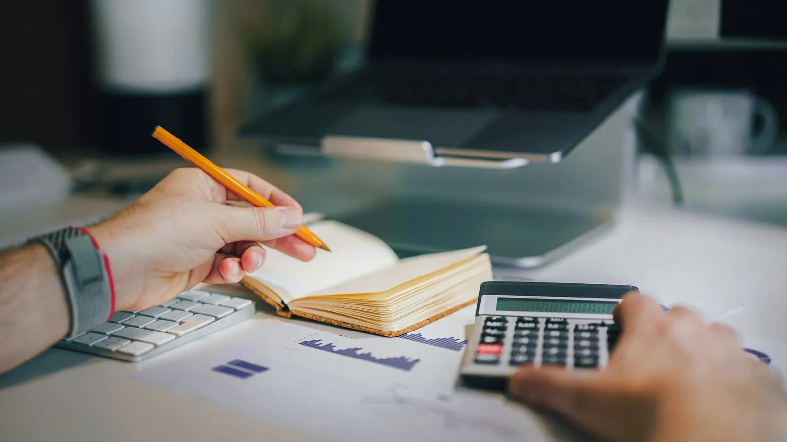 Person using a calculator beside notes and financial charts